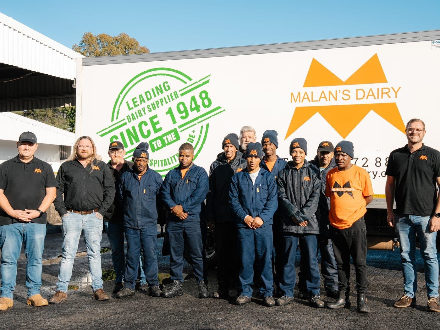 The Malan's Dairy warehouse and driver crew by a branded truck