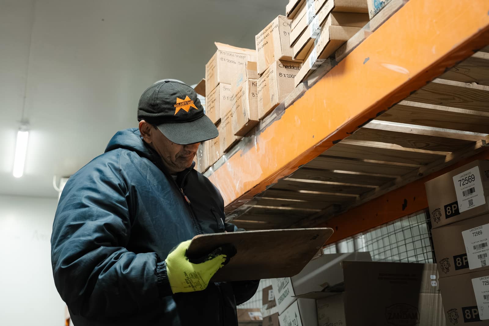 A Malan's Dairy staffer in a branded cap checking stock in the cold store
