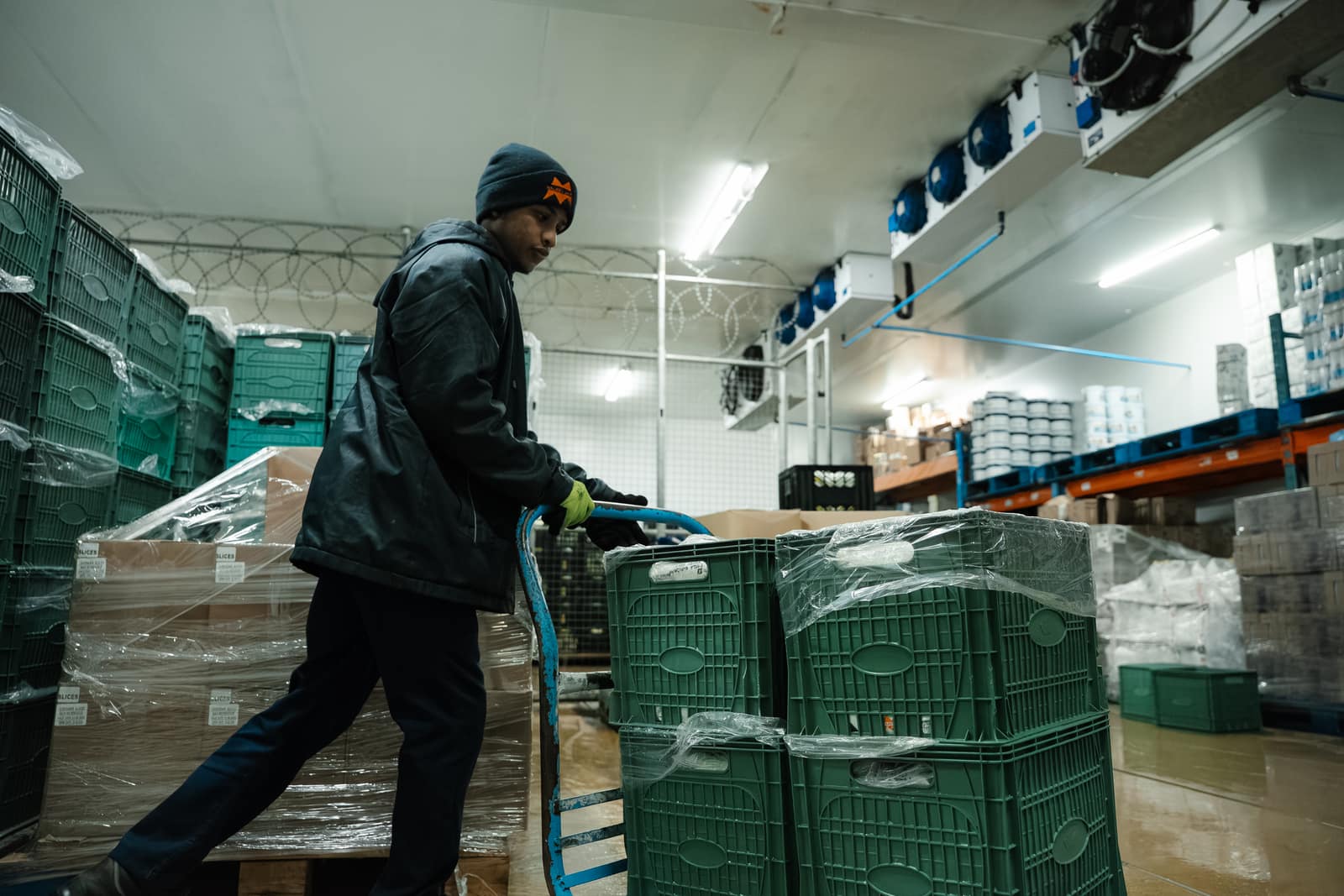 A Malan's Dairy warehouse team member moving crates through the cold room