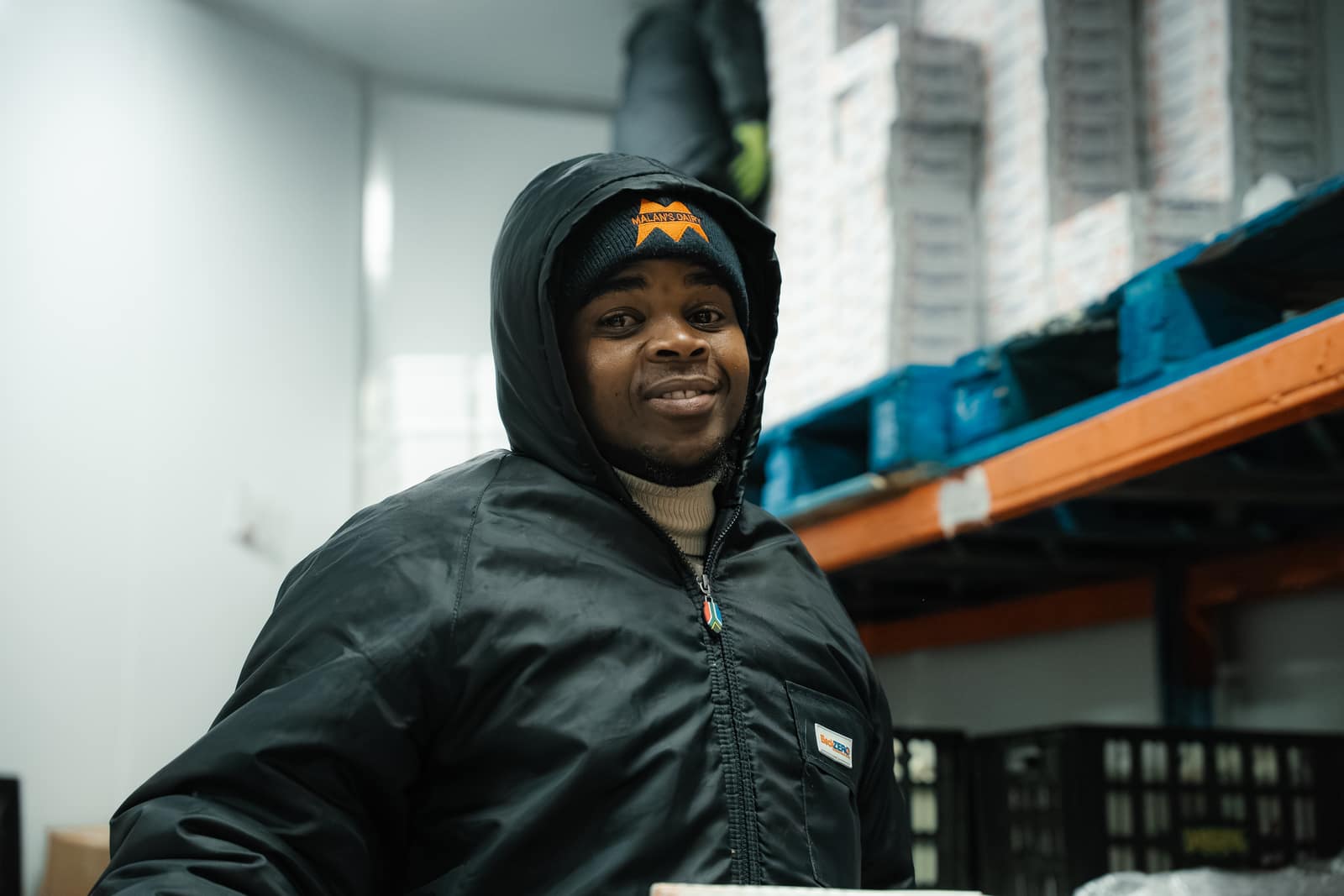 A smiling Malan's Dairy cold-room team member in a branded beanie