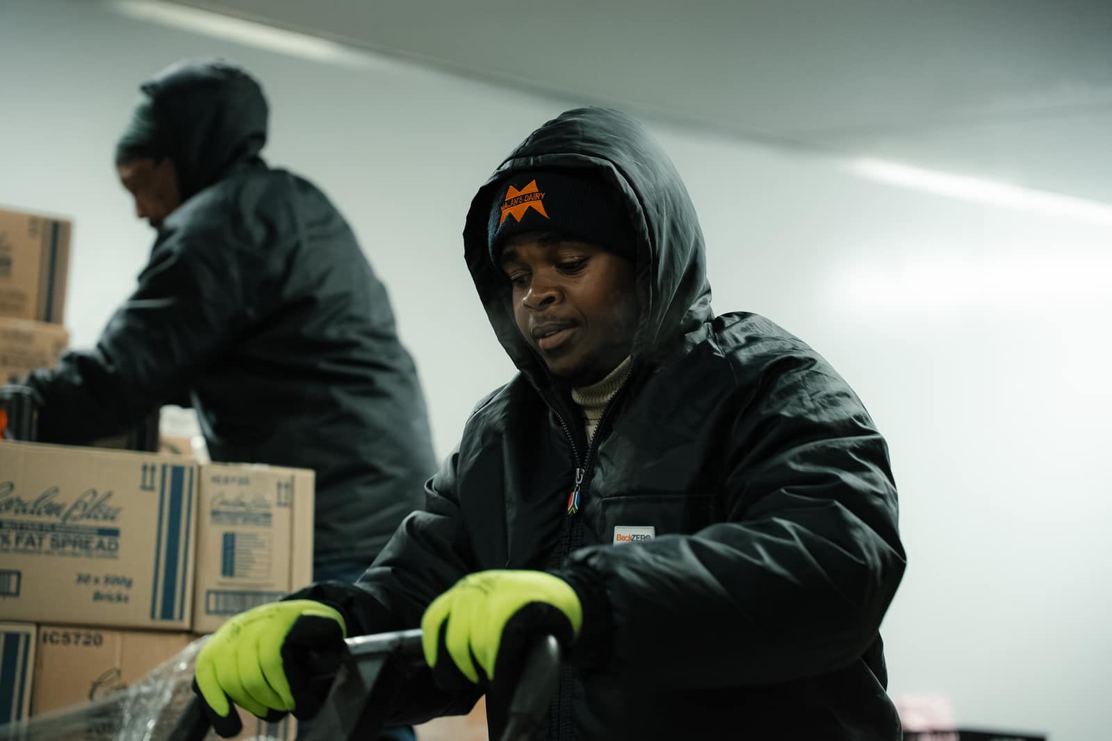 A Malan's Dairy cold-room worker moving stock with a colleague behind