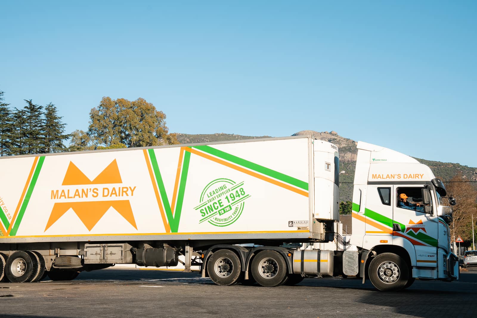 A Malan's Dairy driver waving from the cab of a branded truck