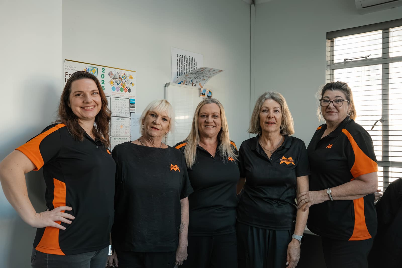 A group of Malan's Dairy office and sales staff in branded shirts