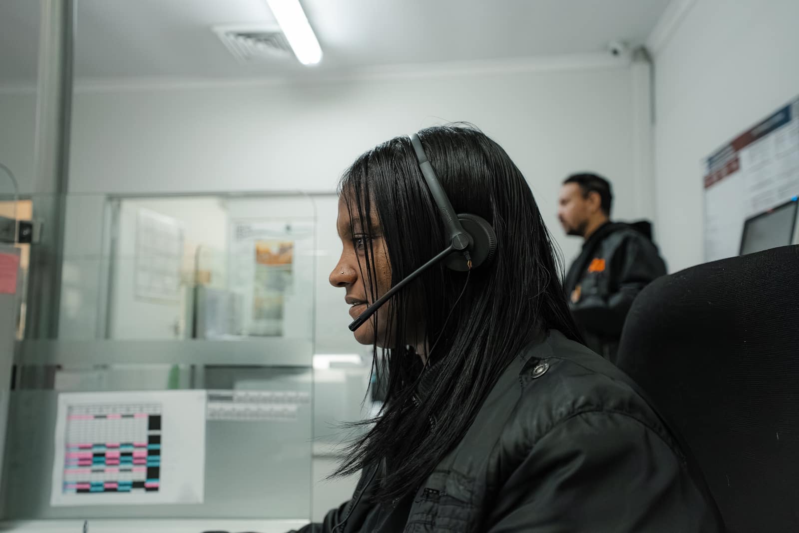 A Malan's Dairy telesales rep on a headset with a colleague behind