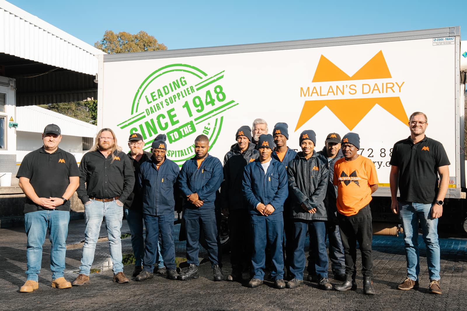 The Malan's Dairy warehouse crew in overalls in front of a branded truck