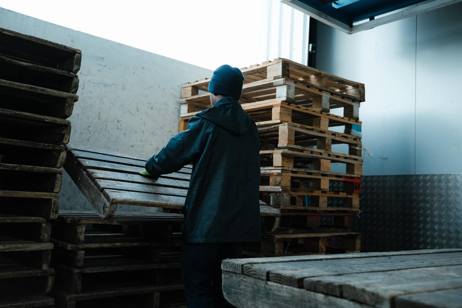 A Malan's Dairy warehouse worker in a branded beanie handling pallets