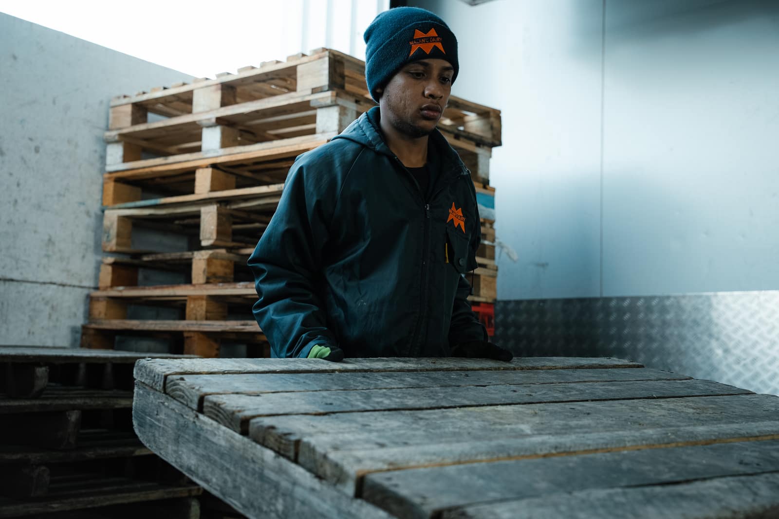A young Malan's Dairy warehouse staffer in a branded jacket by the pallets